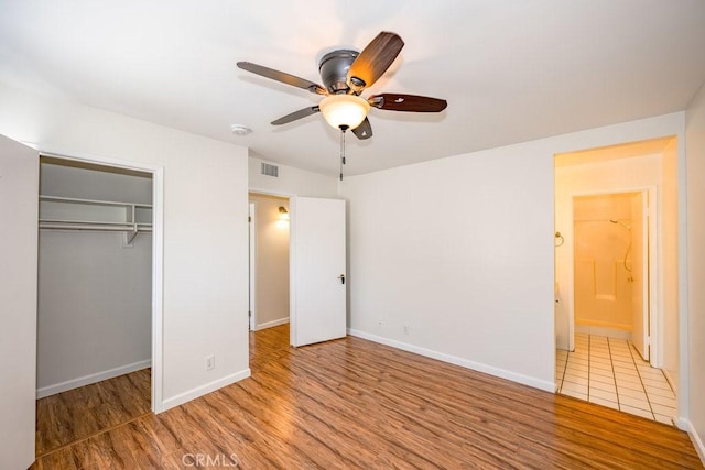 unfurnished bedroom featuring baseboards, visible vents, ceiling fan, wood finished floors, and a closet