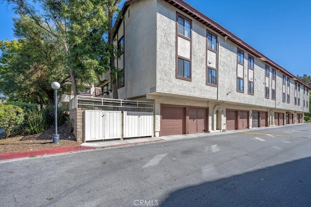 view of property exterior with community garages and stucco siding