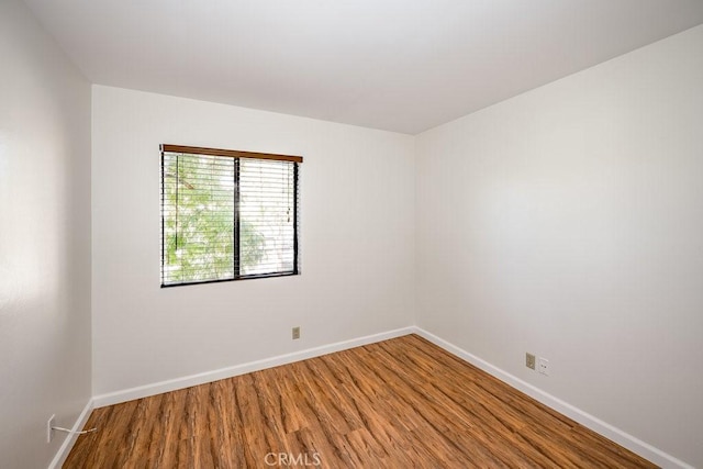 spare room with baseboards and wood finished floors