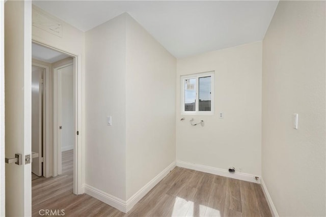 laundry area featuring laundry area, baseboards, light wood-style flooring, and electric dryer hookup