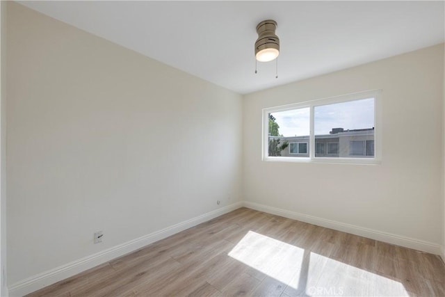 unfurnished room with light wood finished floors, baseboards, and a ceiling fan