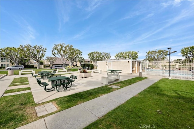 view of property's community featuring a lawn, a patio area, fence, a residential view, and a swimming pool