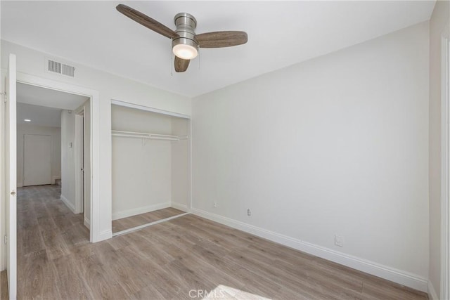 unfurnished bedroom with light wood-type flooring, baseboards, visible vents, and a closet