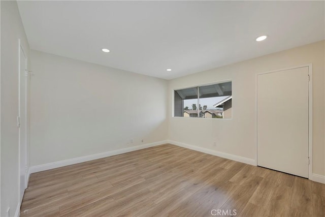 empty room with baseboards, wood finished floors, and recessed lighting