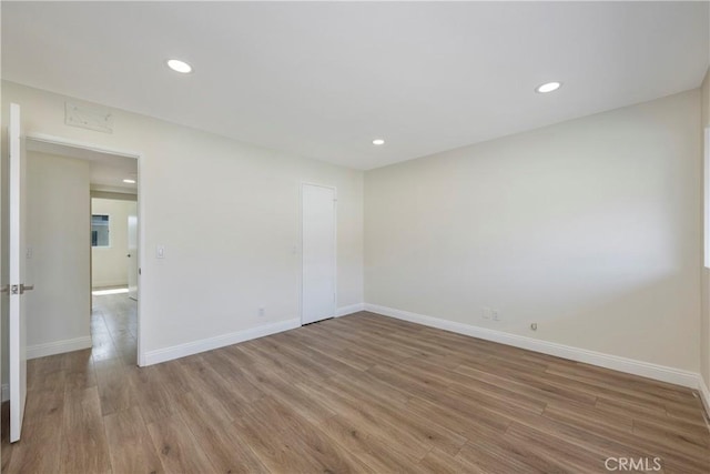 spare room with baseboards, wood finished floors, and recessed lighting