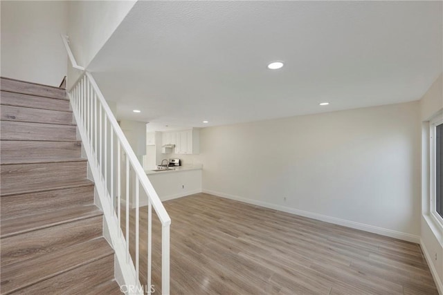 staircase with baseboards, wood finished floors, and recessed lighting