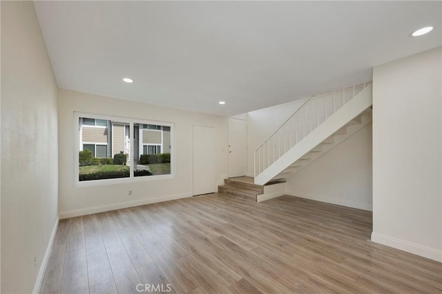 spare room featuring stairs, baseboards, wood finished floors, and recessed lighting