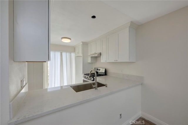 kitchen featuring light stone counters, stainless steel range with gas cooktop, white cabinets, under cabinet range hood, and baseboards