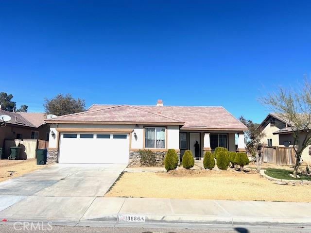 view of front of property featuring a garage, fence, concrete driveway, and stucco siding