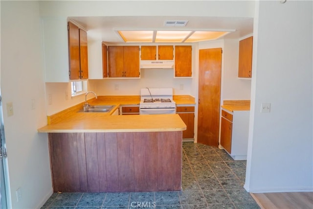 kitchen with light countertops, visible vents, white range with gas cooktop, a sink, and under cabinet range hood