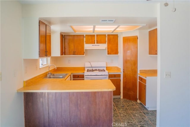 kitchen with white gas range oven, visible vents, light countertops, under cabinet range hood, and a sink