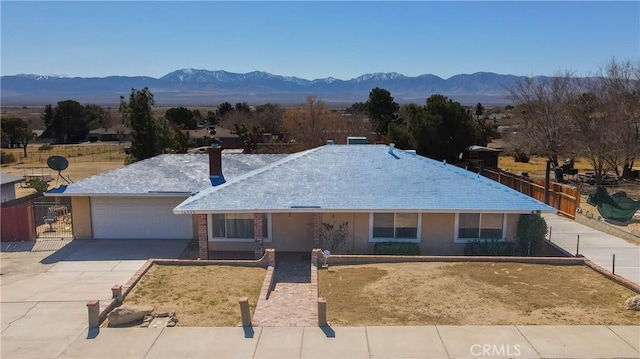 ranch-style home featuring concrete driveway, a mountain view, an attached garage, and fence