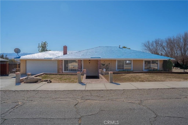 view of front of property featuring a garage, fence, a chimney, and stucco siding