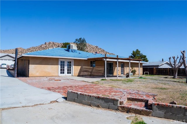 rear view of house with central AC, fence, french doors, stucco siding, and a patio area