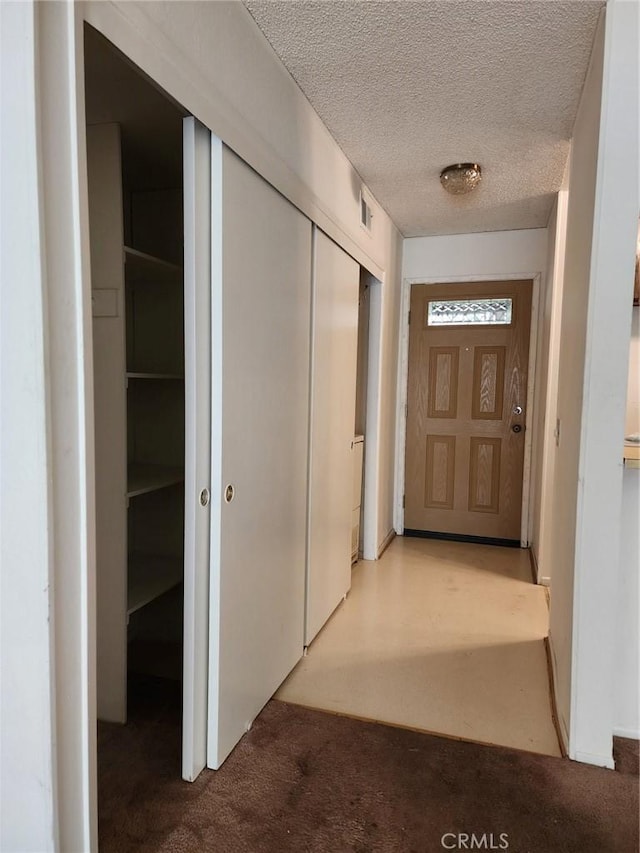 hall featuring visible vents, a textured ceiling, and carpet flooring