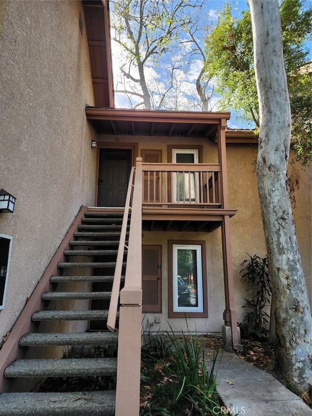 doorway to property with a balcony and stucco siding