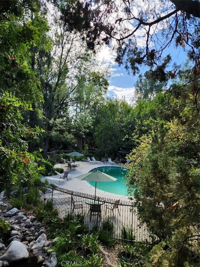 pool with a patio area and fence