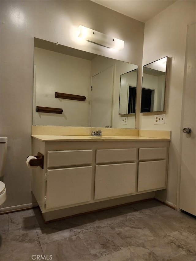 bathroom with vanity, toilet, and baseboards