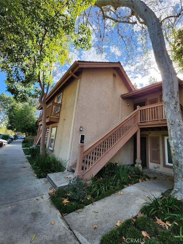 view of side of home with stucco siding and stairs