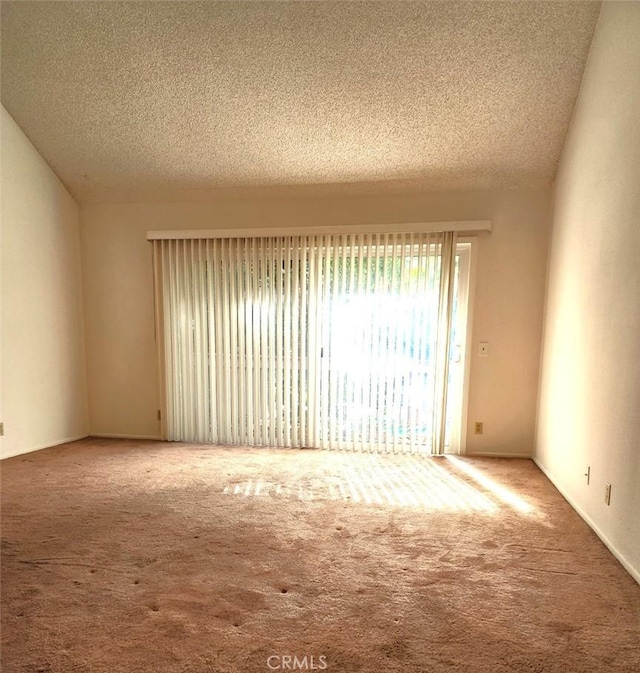 carpeted spare room featuring a textured ceiling and vaulted ceiling