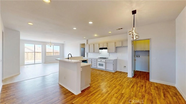 12912 Amador St, Victorville, CA 92392 - kitchen with oven, visible vents, a center island with sink, light wood-style floors, and an inviting chandelier