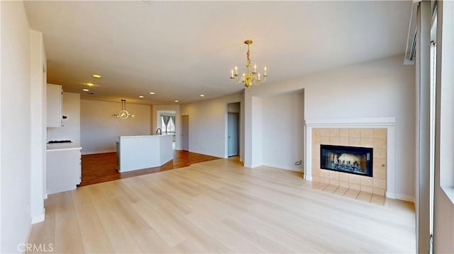 12912 Amador St, Victorville, CA 92392 - unfurnished living room with recessed lighting, light wood-style floors, an inviting chandelier, a fireplace, and baseboards