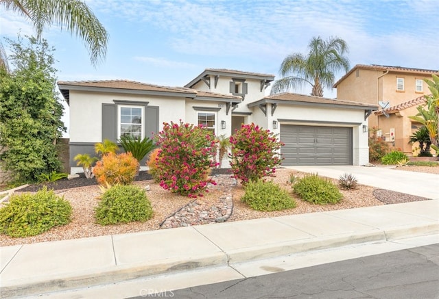 view of front of home featuring a garage, driveway, a tile roof, and stucco siding