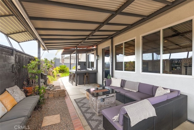 view of patio featuring fence, outdoor dry bar, and an outdoor living space with a fire pit