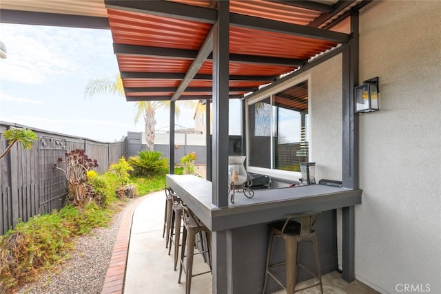 view of patio with fence and outdoor dry bar