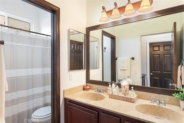 full bathroom featuring double vanity, a sink, and toilet