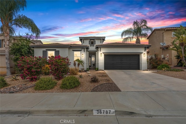 prairie-style home with an attached garage, concrete driveway, and stucco siding