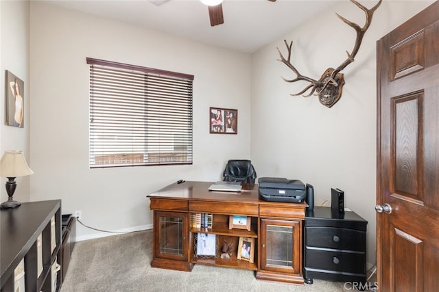 carpeted office with ceiling fan and baseboards