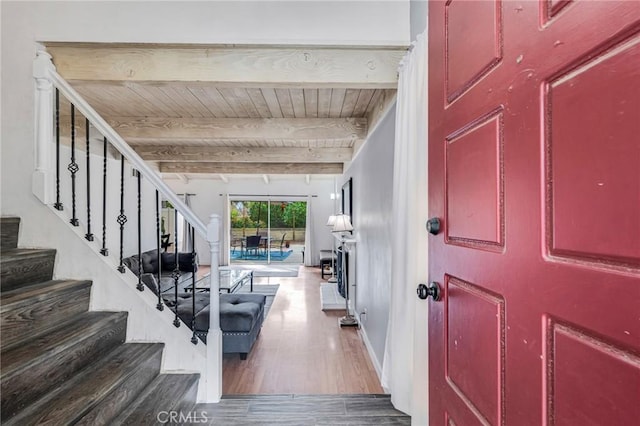 entryway featuring stairway, beamed ceiling, wooden ceiling, and wood finished floors