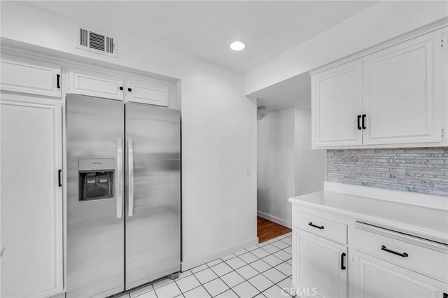 kitchen with visible vents, decorative backsplash, stainless steel fridge with ice dispenser, light countertops, and white cabinetry