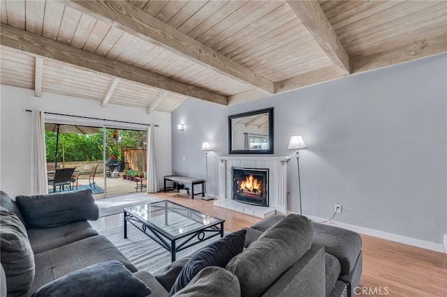 living area featuring wood ceiling, baseboards, wood finished floors, and a tile fireplace