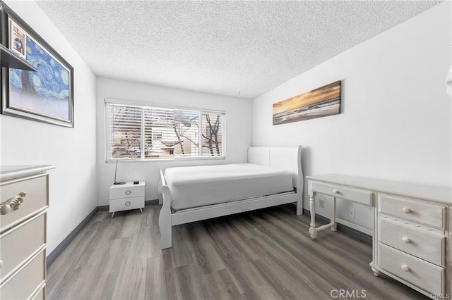 bedroom with a textured ceiling, wood finished floors, and baseboards