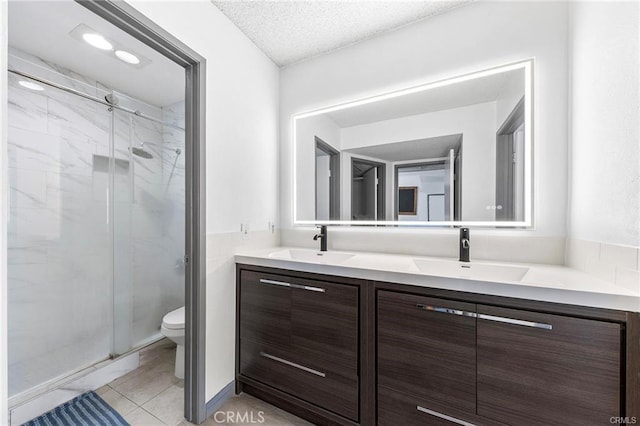 full bathroom featuring double vanity, a stall shower, a sink, and toilet