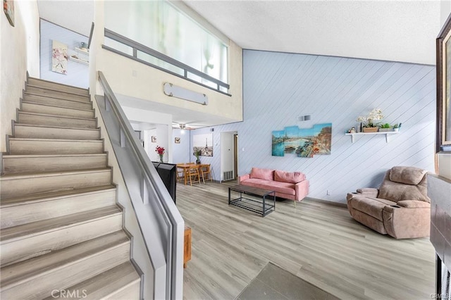 stairs featuring visible vents, a high ceiling, and wood finished floors