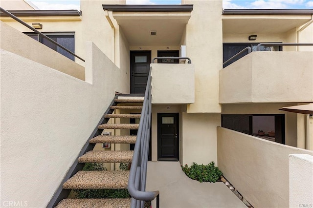 doorway to property with a balcony and stucco siding