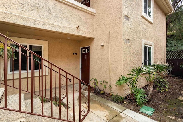 entrance to property with fence and stucco siding