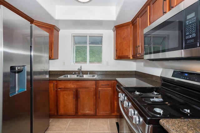 800 Sea Cliff Way Unit 801, Oceanside, CA 92056 - kitchen with stainless steel appliances, a tray ceiling, brown cabinetry, light tile patterned floors, and dark stone counters