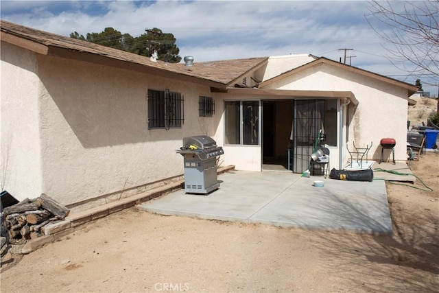 rear view of house featuring a patio and stucco siding