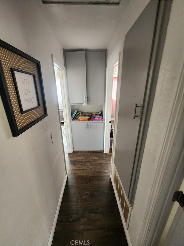 hallway with baseboards and dark wood-style flooring