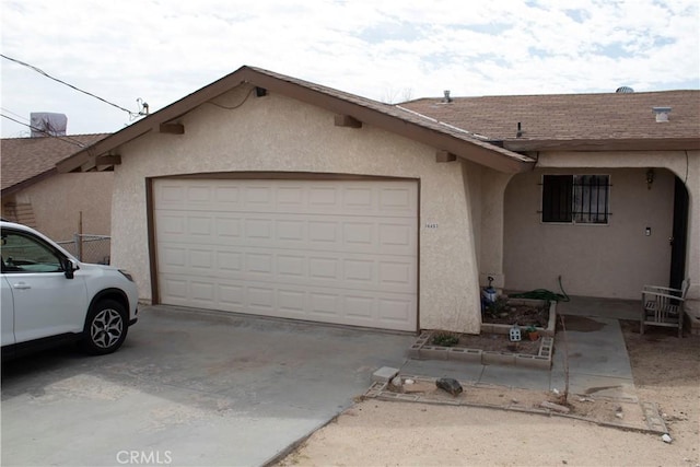 view of front of home featuring concrete driveway, roof with shingles, an attached garage, and stucco siding