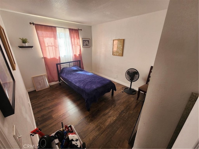 bedroom featuring wood-type flooring, baseboards, and a textured ceiling