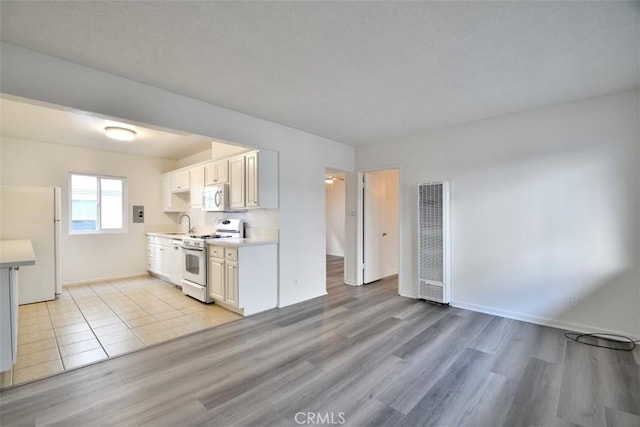 kitchen with light countertops, visible vents, light wood-style floors, a sink, and white appliances