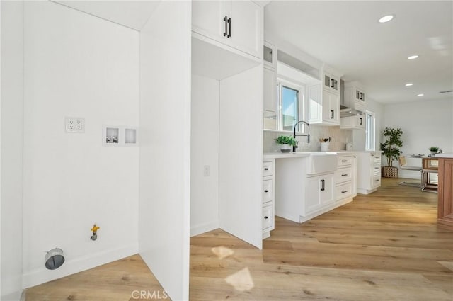 interior space featuring wood finished floors, backsplash, a sink, and recessed lighting