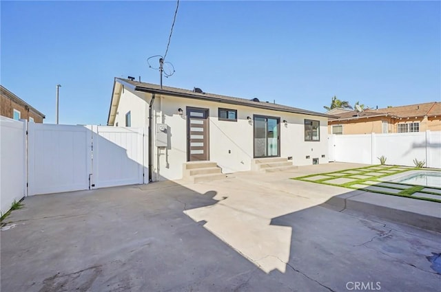 back of house with stucco siding, entry steps, a gate, a patio area, and a fenced backyard