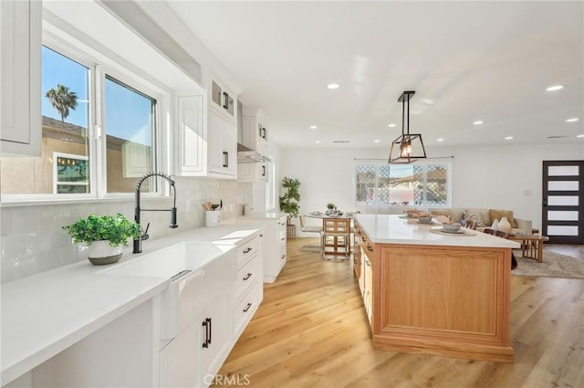 kitchen featuring light wood-style floors, glass insert cabinets, a sink, and a kitchen island