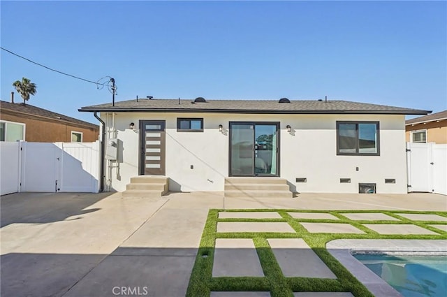 rear view of property with entry steps, stucco siding, a fenced in pool, a gate, and a patio area